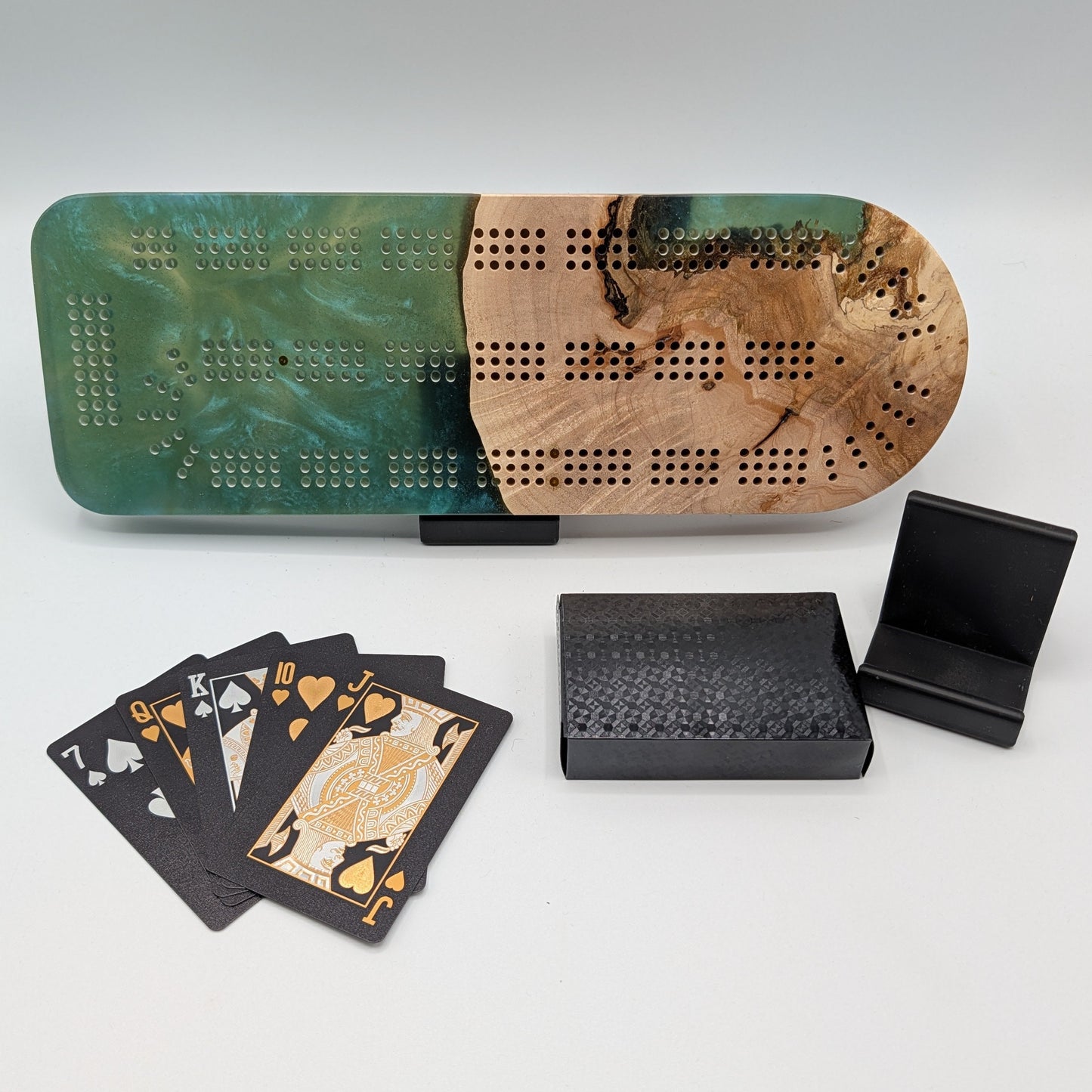 Cribbage board with playing cards and black boxes on a white surface