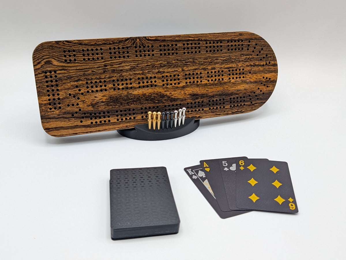 Bocote cribbage board with bold grain, displayed with its stand, pegs and playing cards.