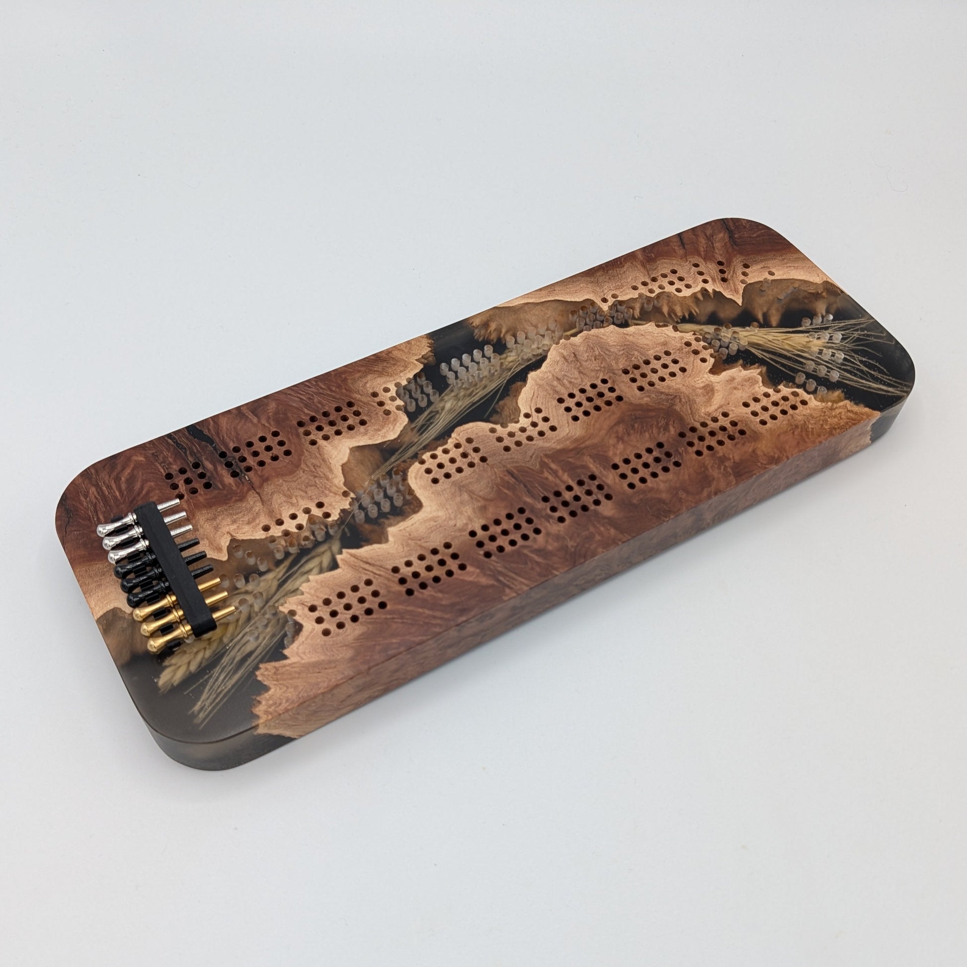 Wooden cribbage board with pegs on a white surface