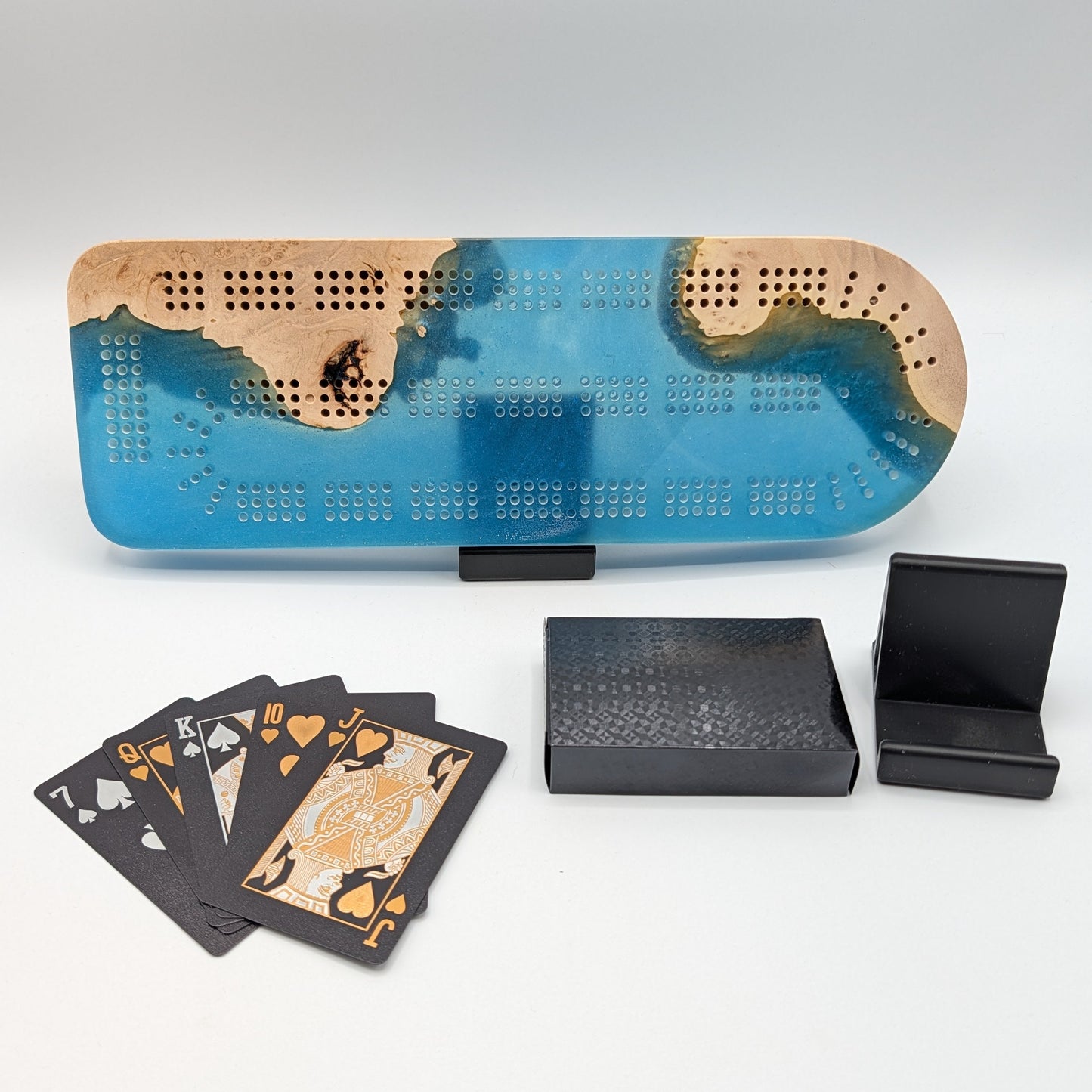 Blue and brown board game box with playing cards and black boxes on a white surface