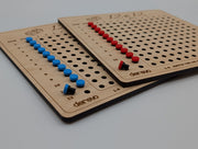 Close view of two engraved 12×12 wooden boards with red and blue markers and dark edges