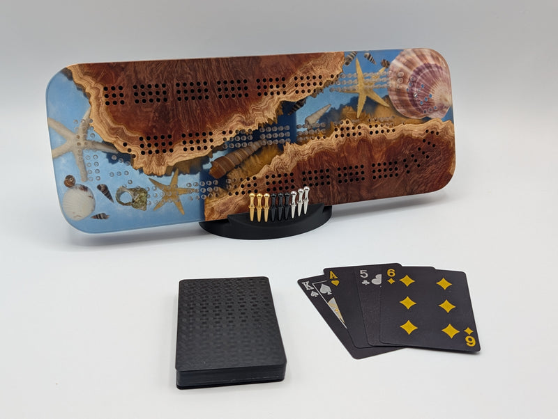 Ocean-themed Imprint cribbage board with Australian red mallee burl, blue epoxy, shells and starfish details.