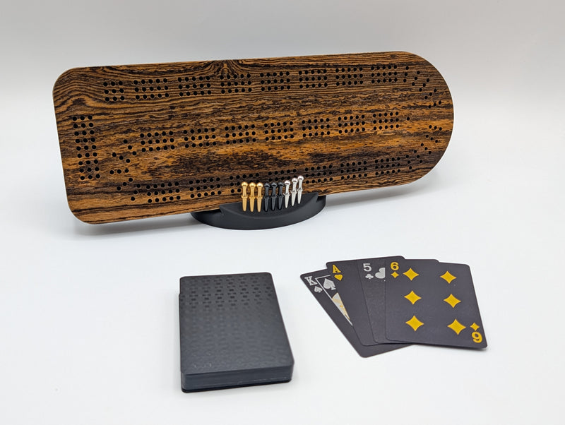 Bocote cribbage board with bold grain, displayed with its stand, pegs and playing cards.
