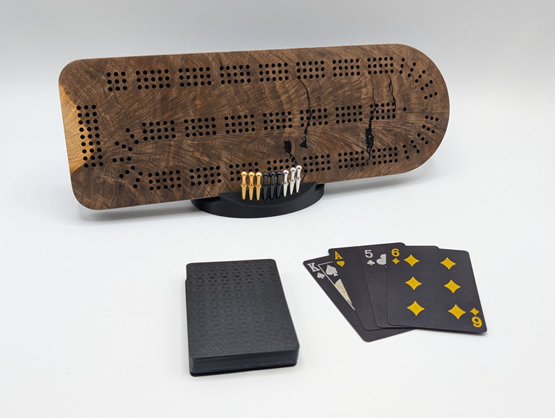 Canadian black walnut cribbage board displayed with its pegs, display stand and playing cards.