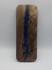 Reverse of the Canadian black walnut cribbage board with a branching cobalt blue resin channel through its figured grain.