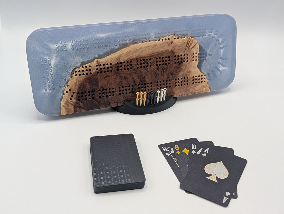 Origin cribbage board in Australian red mallee burl and storm blue epoxy, displayed with pegs, cards and stand.