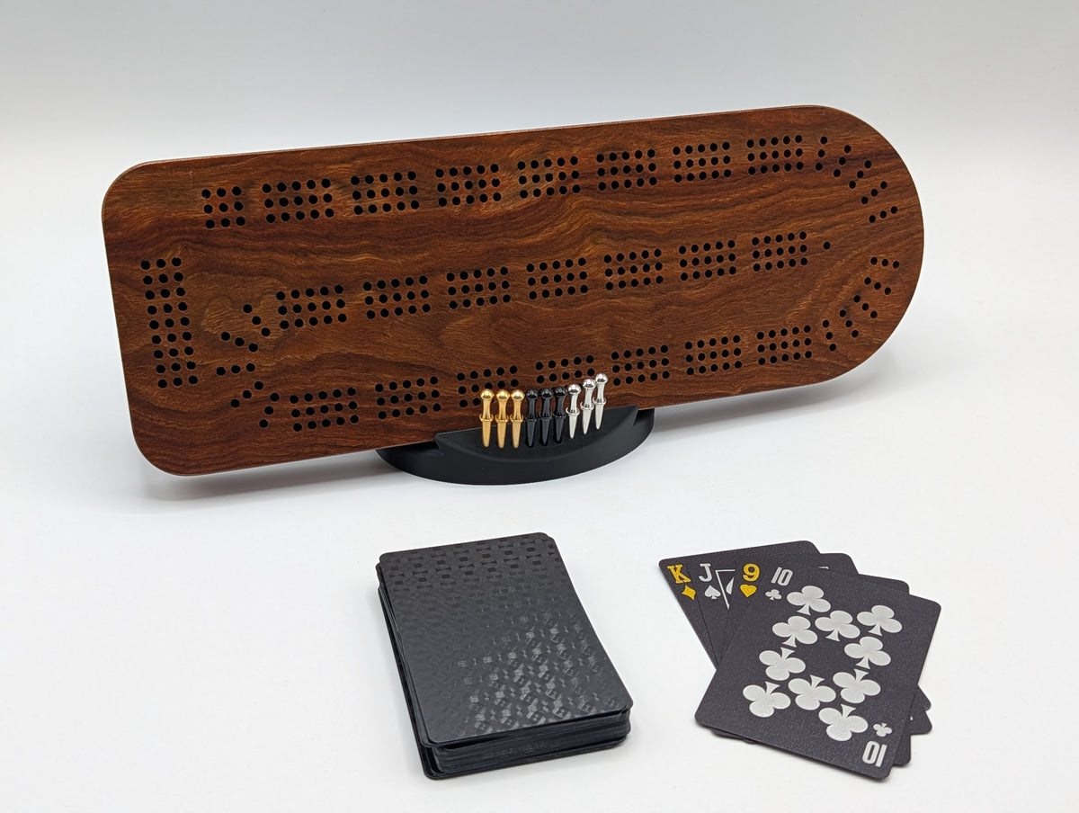 Caribbean rosewood Standard cribbage board showing three-track holes, flowing dark grain, metal pegs and black playing cards
